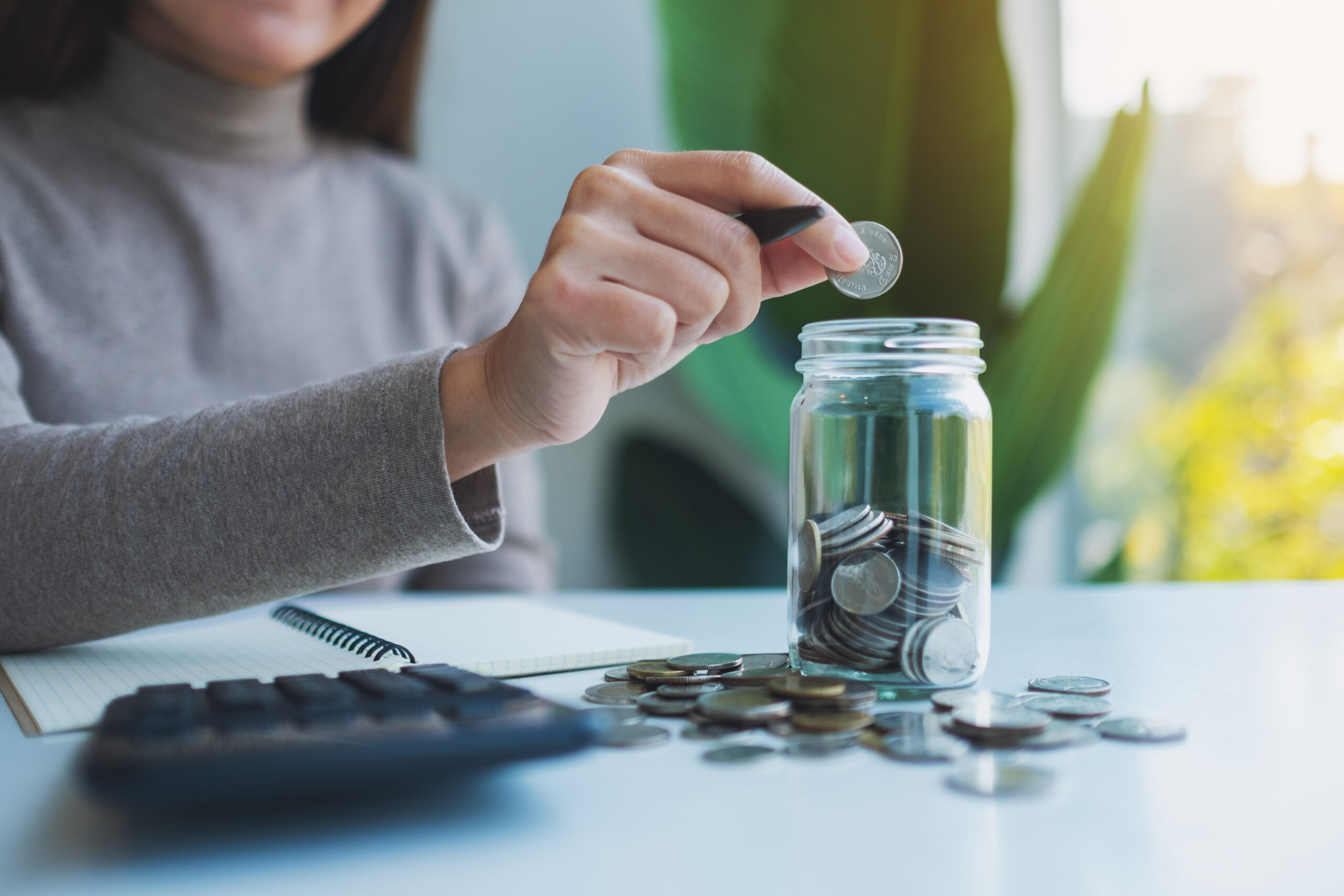 An actress dropping a coin in a glass jar while she figures out her finances