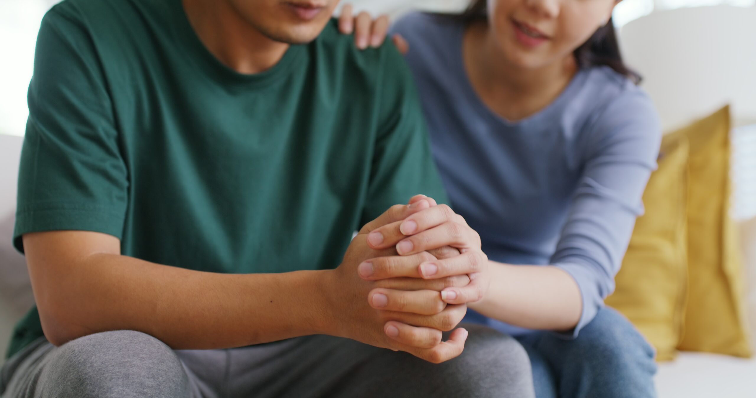 A woman supporting a stressed man with their hands clasped