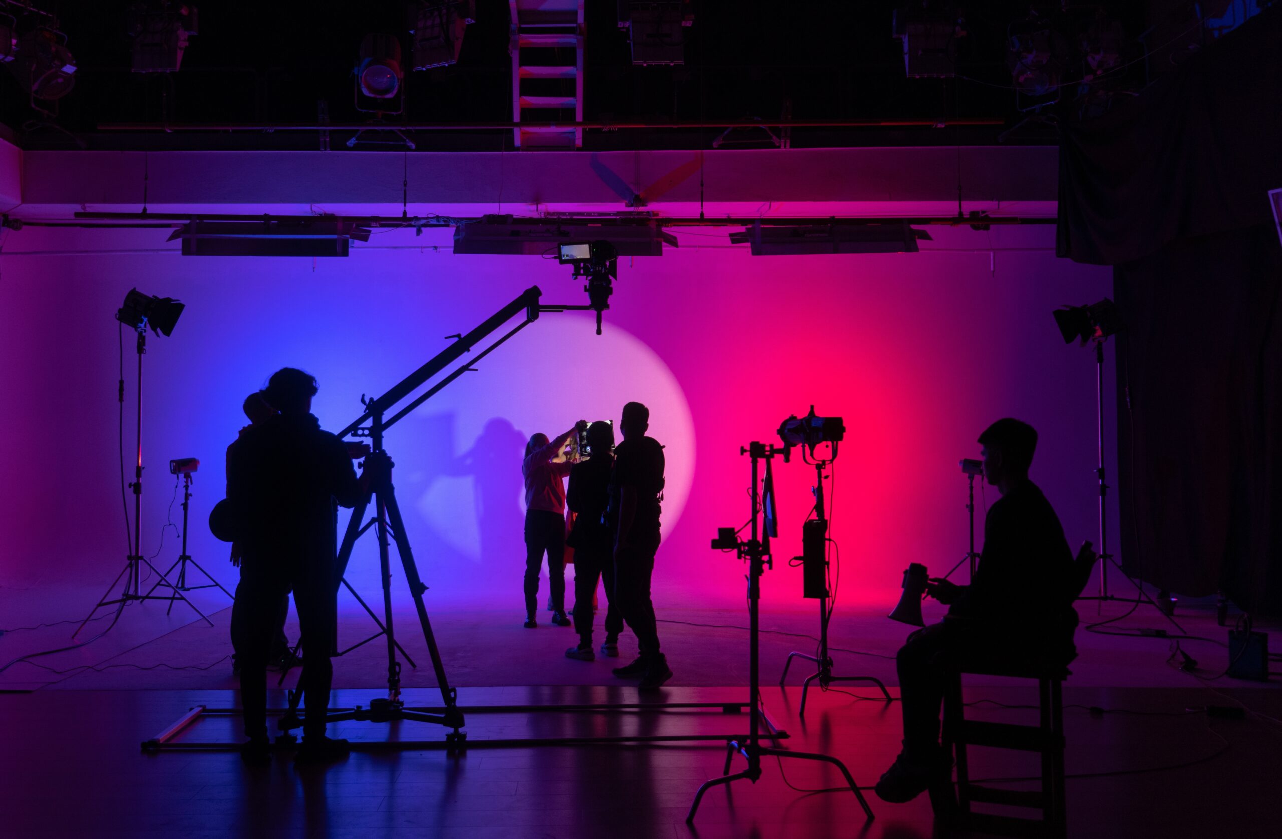Silhouettes of crew working on a film set in blue and pink light