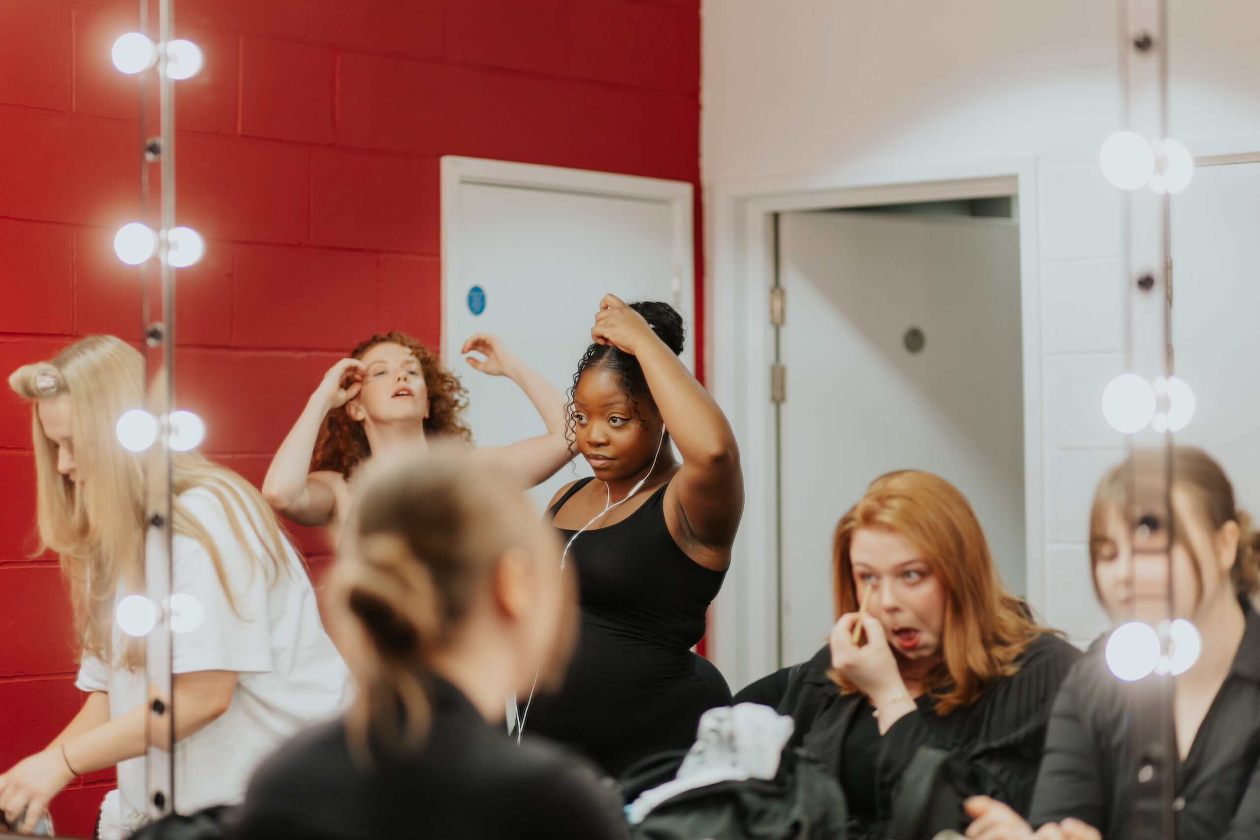 Young actresses getting themselves ready in front of a mirror in a dressing room for their stage performances