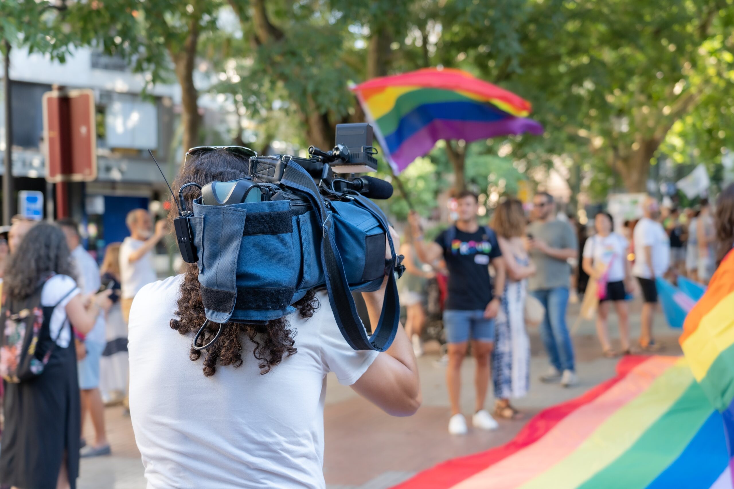 A camera filming someone waving a Pride flag