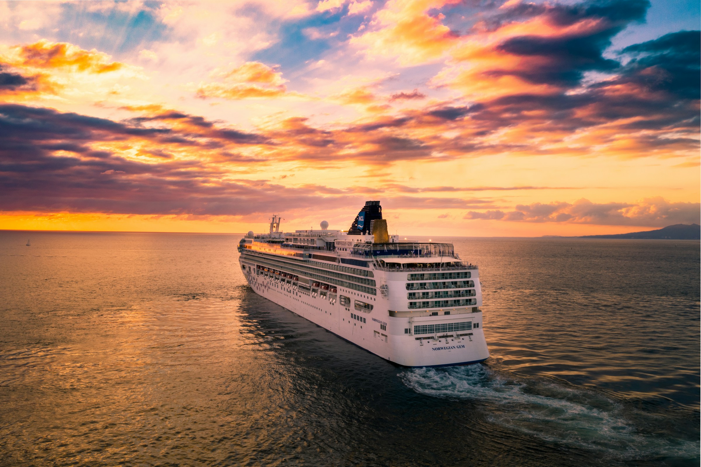 A cruise ship sailing towards the horizon while the sun sets